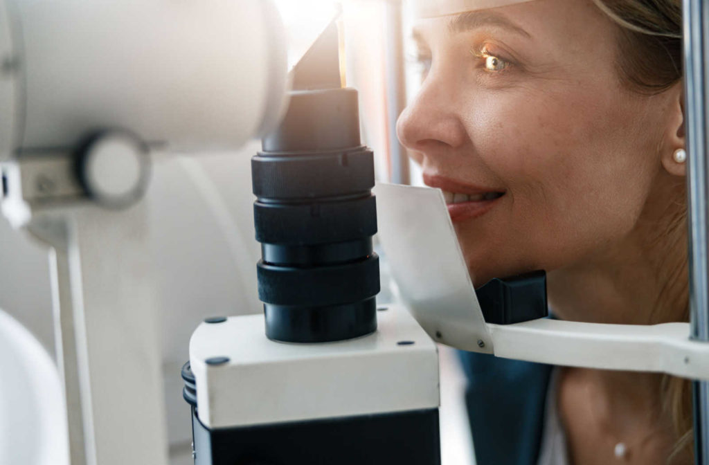 A female patient gets her eyes examined for specialty contact lens while resting her chin on the equipment.