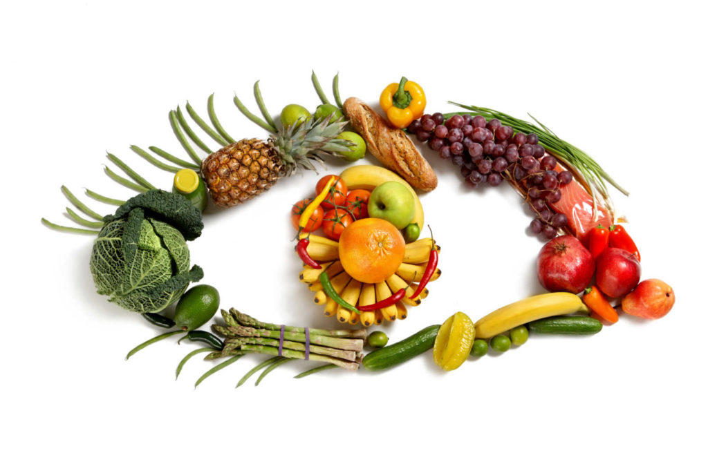 A selection of vegetables, fruits, and fish that are rich in vitamins and minerals that are good for the eyes and laid out in the shape of an eye