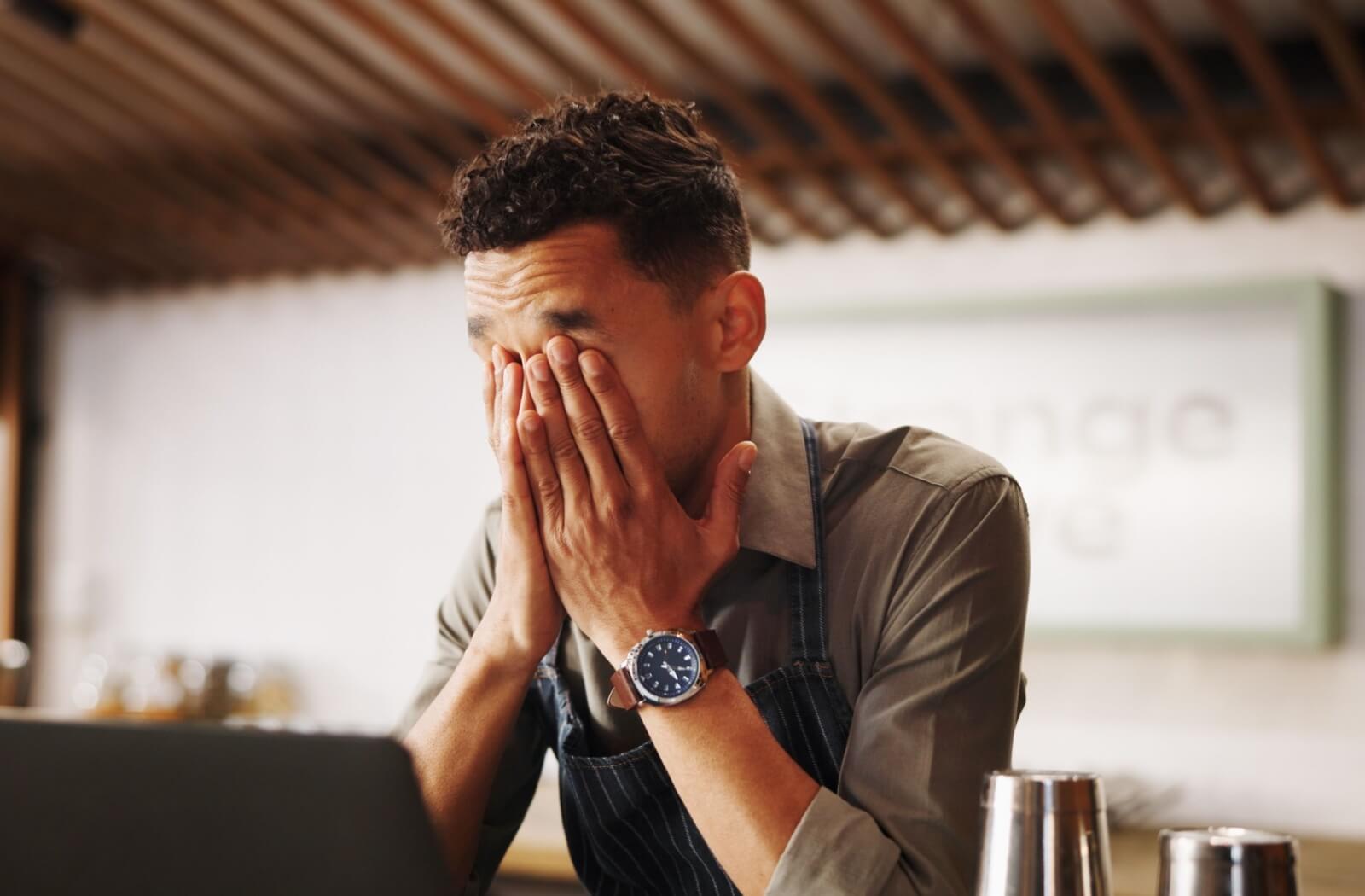 Man experiencing eye strain while working on a laptop.